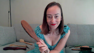 Miss Jenn Davis holding her clothing brush as she smiles before your spanking
